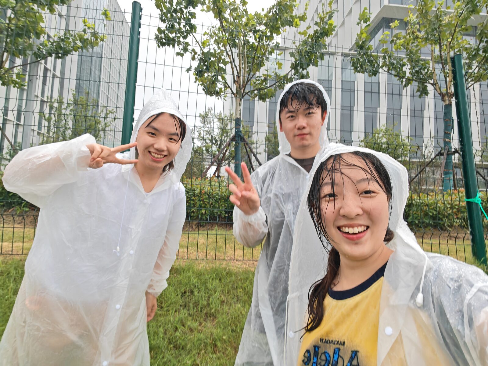 Three Tongji MRL team members wearing rain ponchos during an outdoor field test
