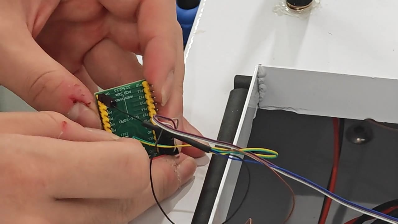 Hands connecting wiring to an electronics board inside the USV